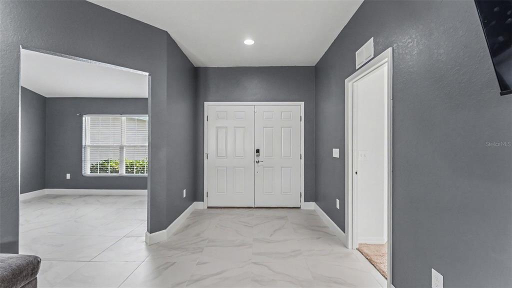 An entryway with gray walls, white trim, and light-colored tile flooring leads to double doors — 2048 WINDING RIVER COVE, BARTOW, FL