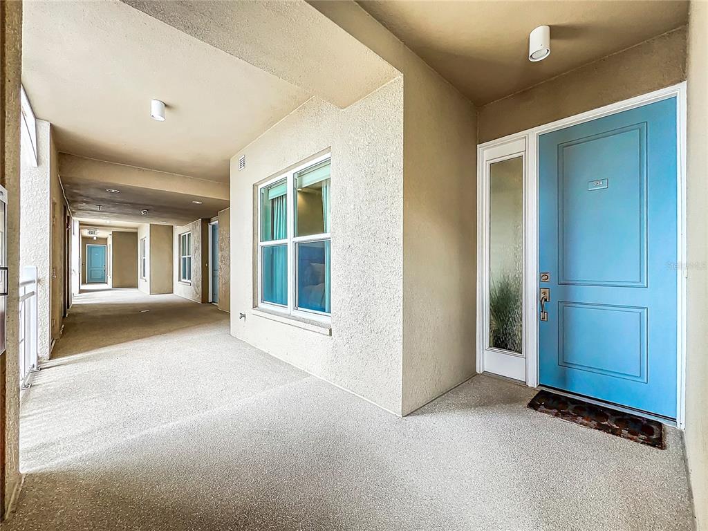 A light blue front door opens onto a covered outdoor apartment building walkway — 10530 BOARDWALK LOOP UNIT 304, BRADENTON, FL