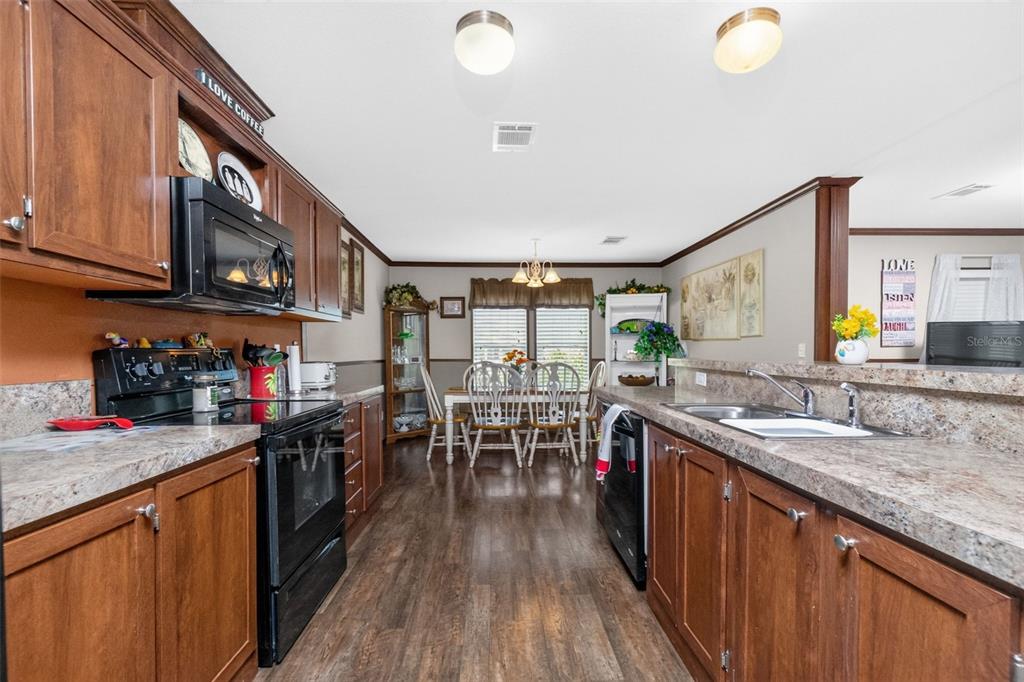 A covered porch with wicker chairs overlooks a canal and tropical landscaping — 1268 SEAGULL DRIVE, ENGLEWOOD, FL