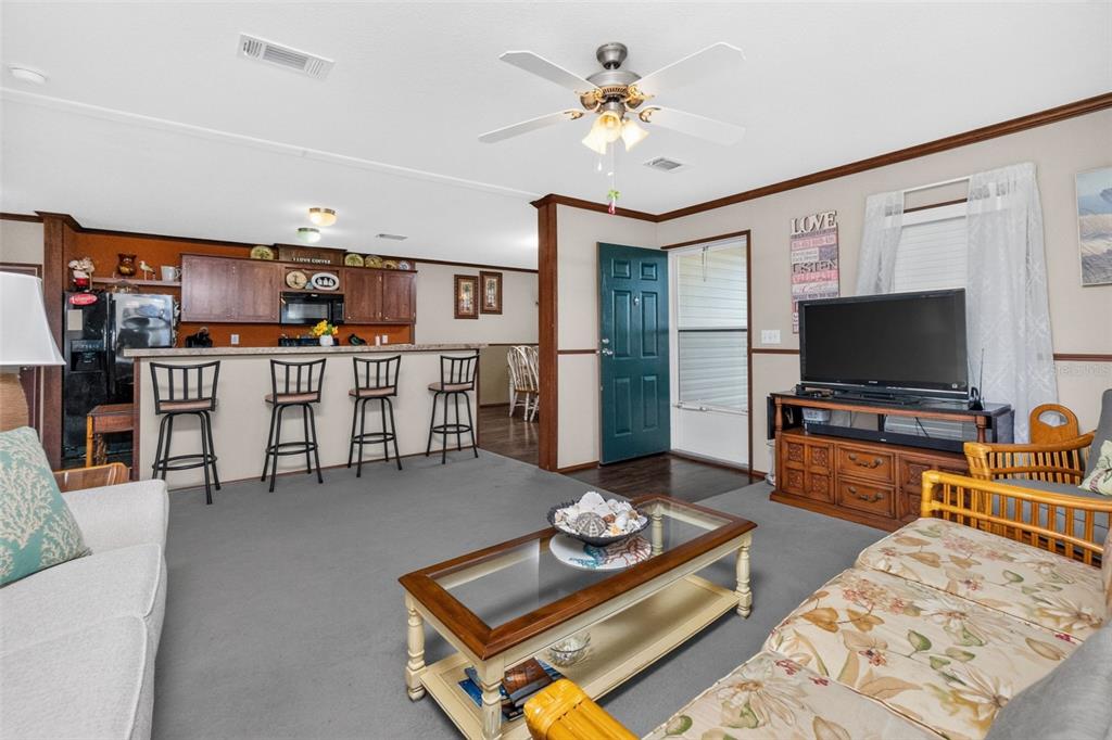 A kitchen with wood cabinets and laminate countertops opens to a dining area — 1268 SEAGULL DRIVE, ENGLEWOOD, FL