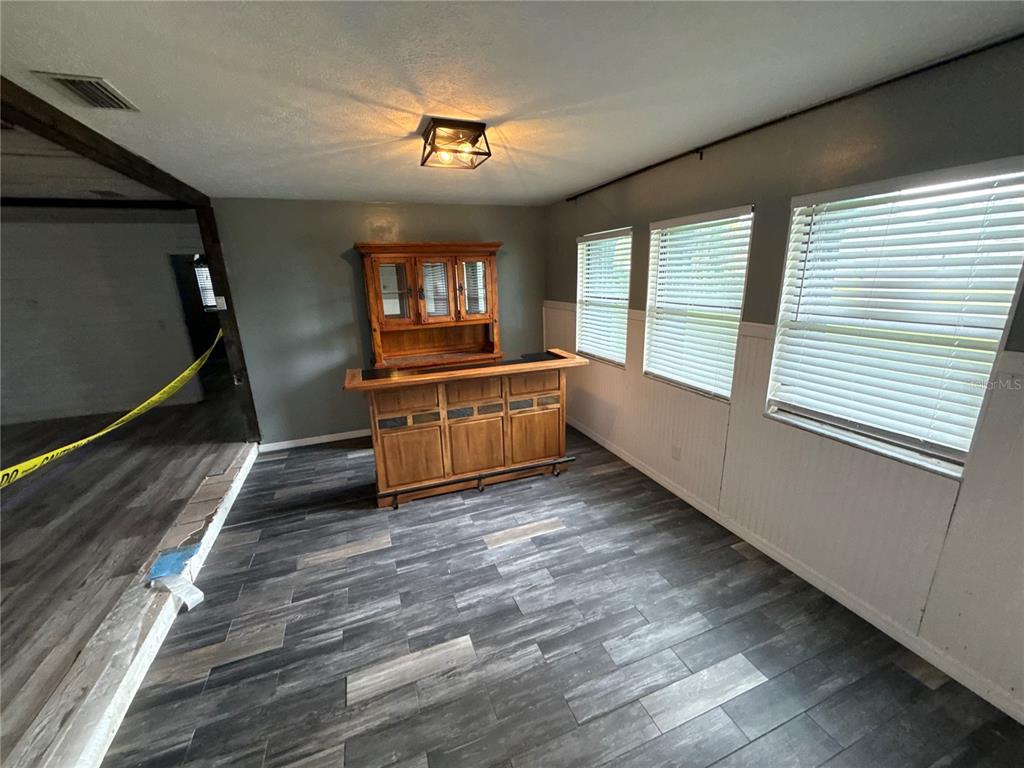 A room with a wooden bar, a hutch, and gray wood-look flooring — 1806 N WATERMAN DRIVE, VALRICO, FL