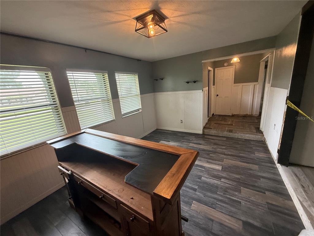 A room features wood-look flooring, white wainscoting, a wooden bar counter, and a ceiling light — 1806 N WATERMAN DRIVE, VALRICO, FL