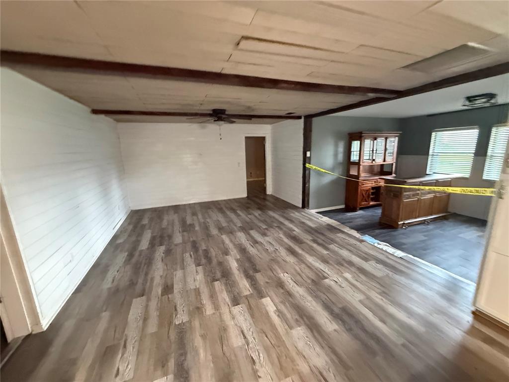 A living room with wood-look flooring, white paneled walls, and a ceiling with exposed beams — 1806 N WATERMAN DRIVE, VALRICO, FL
