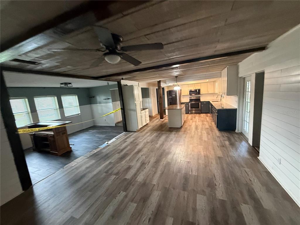 An open-concept kitchen and living area feature wood-look flooring, a ceiling fan, and white cabinetry — 1806 N WATERMAN DRIVE, VALRICO, FL