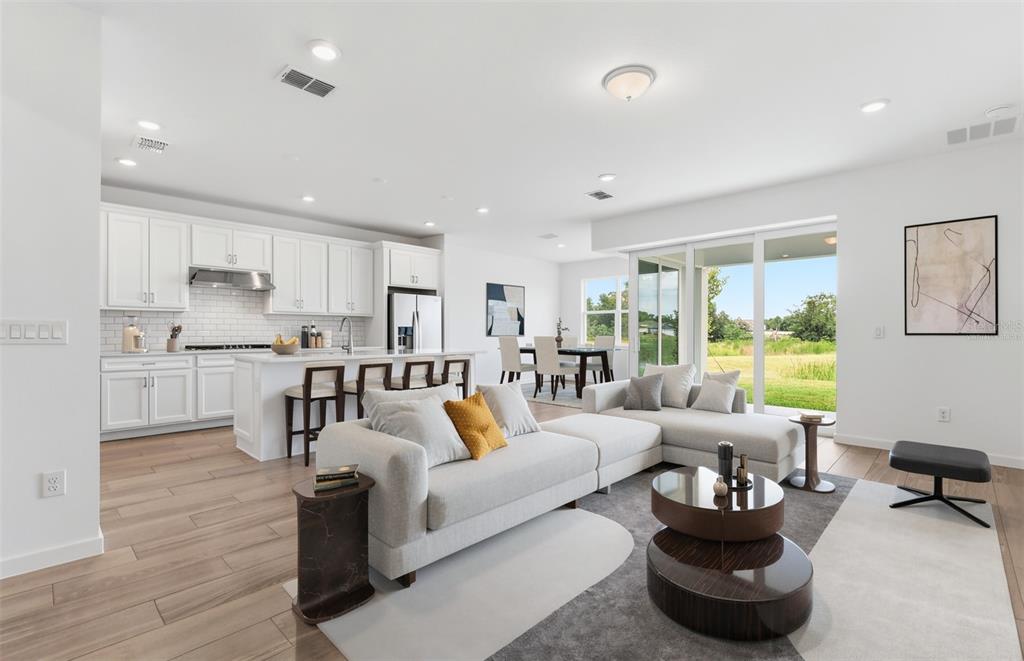 An open-concept living room and kitchen with white cabinetry, light flooring, and sliding glass doors — 37821 CLINCH CIRCLE, ZEPHYRHILLS, FL