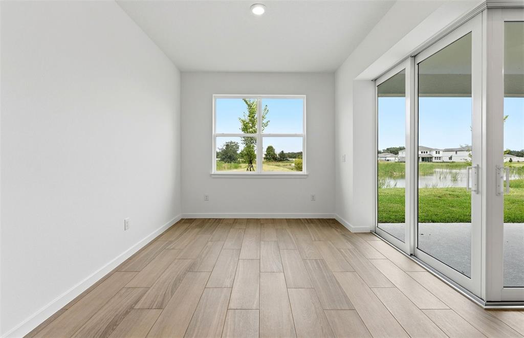 An empty room features light wood-look tile flooring, white walls, a window, and sliding doors — 37821 CLINCH CIRCLE, ZEPHYRHILLS, FL