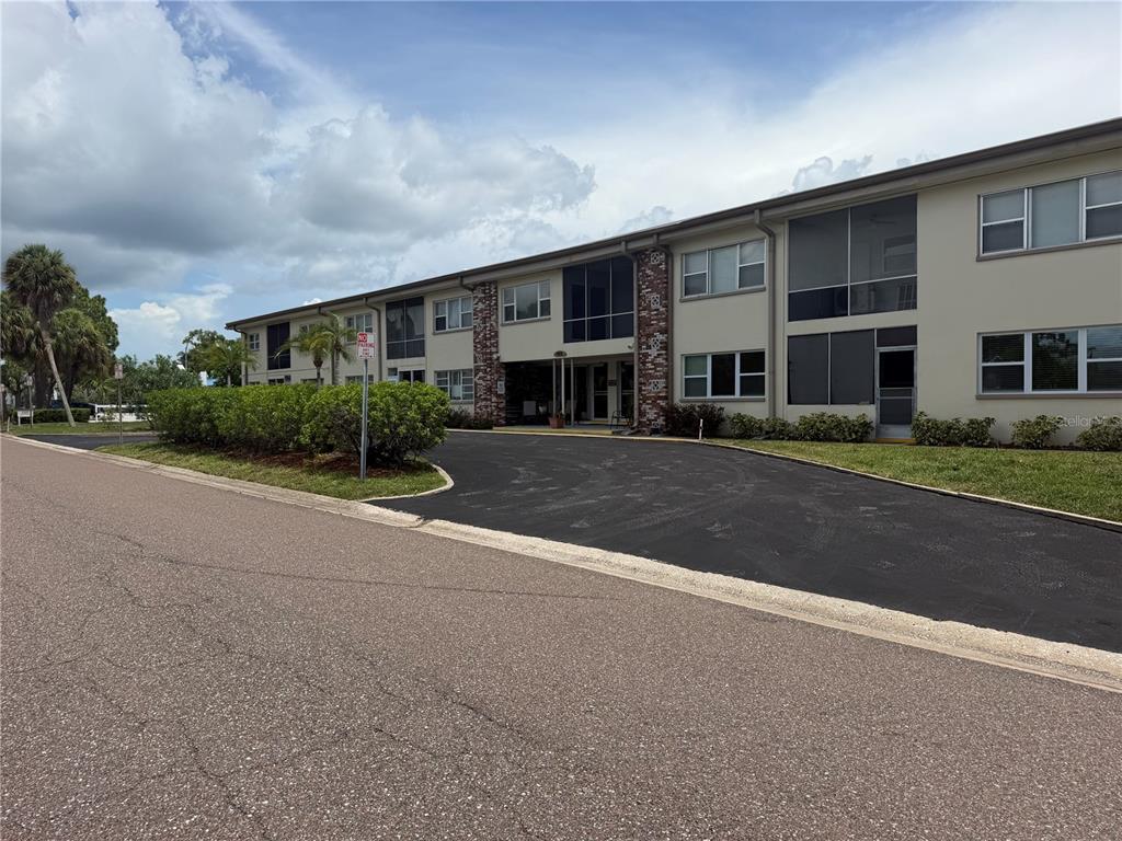 A two-story apartment building with a paved driveway and landscaped bushes in front — 416 73RD AVENUE N UNIT 205, ST PETERSBURG, FL