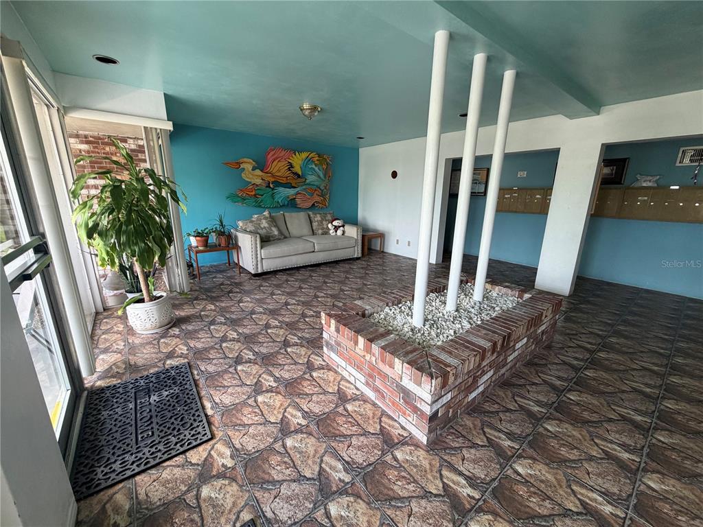 A lobby features a brick planter with white pillars, stone-patterned tile flooring, and teal walls — 416 73RD AVENUE N UNIT 205, ST PETERSBURG, FL
