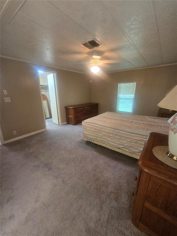 A bedroom features beige walls, gray carpeting, a ceiling fan, and a wooden dresser — 4645 BURNEY DRIVE, HOLIDAY, FL