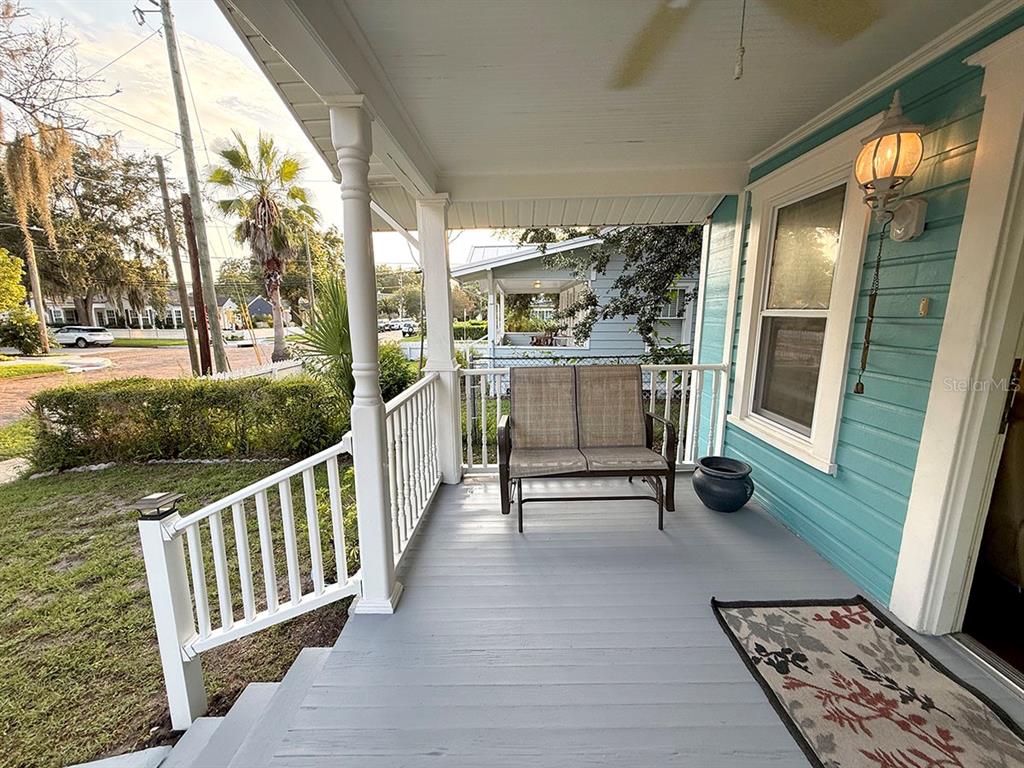 A covered front porch features a gray wooden floor, white railings, and a small bench — 1407 E RIDGEWOOD STREET, ORLANDO, FL