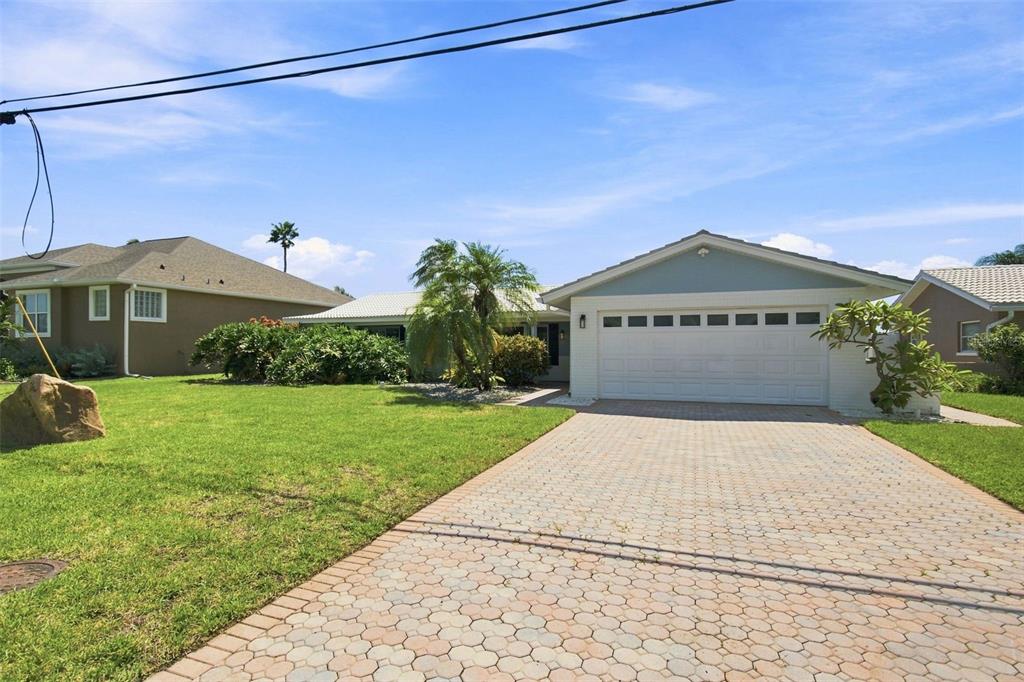 A single-story house with a white garage door and a paved driveway under a blue sky — 11900 7TH STREET E, TREASURE ISLAND, FL
