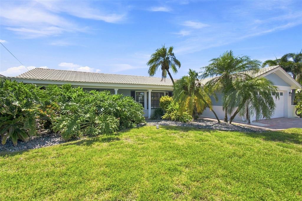 A single-story house with a tiled roof, palm trees, and landscaping in the front yard — 11900 7TH STREET E, TREASURE ISLAND, FL