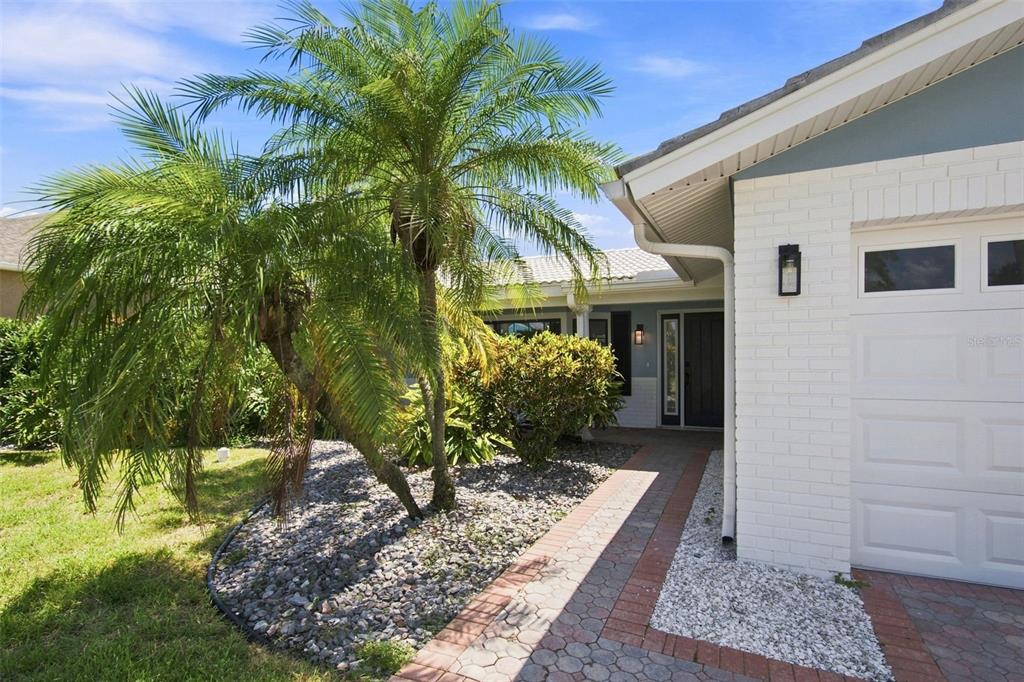 A white brick garage and a paved walkway lead to the front entrance of a home — 11900 7TH STREET E, TREASURE ISLAND, FL