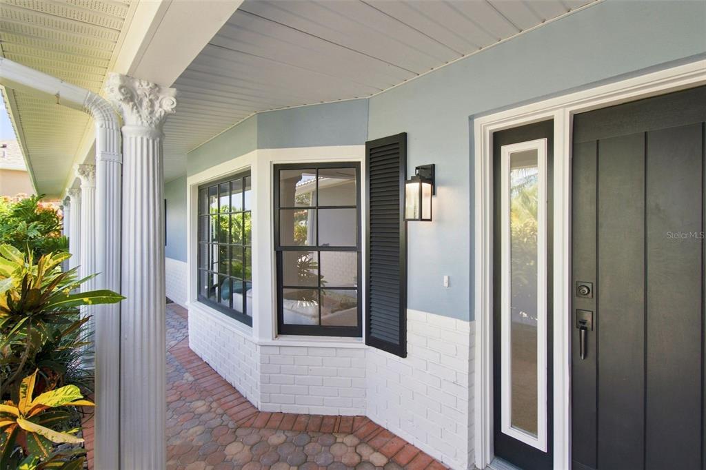 A front porch features a dark door, bay windows, white brick base, and decorative columns — 11900 7TH STREET E, TREASURE ISLAND, FL
