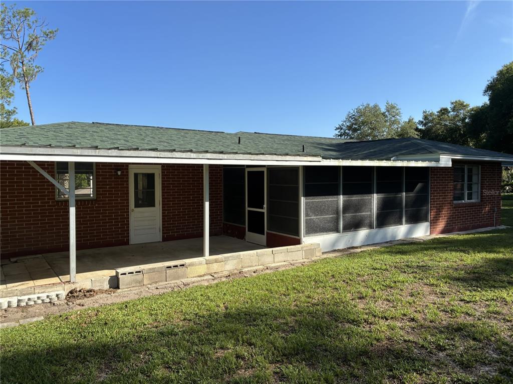 A brick house features a covered patio and an attached screened-in porch in the backyard — 4926 MAGNOLIA RIDGE ROAD, FRUITLAND PARK, FL