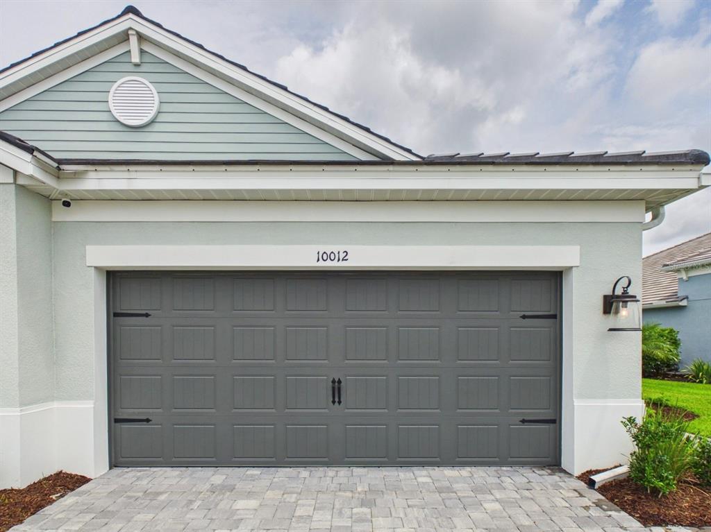A gray garage door with decorative hardware is centered on the exterior of a house — 10012 LAKE WALES CIRCLE, SARASOTA, FL