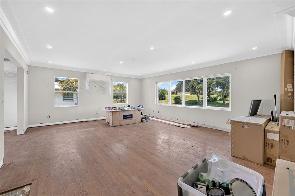 An unfurnished room with hardwood floors, recessed lighting, and large windows overlooking a grassy yard — 2314 S PENINSULA DRIVE, DAYTONA BEACH, FL