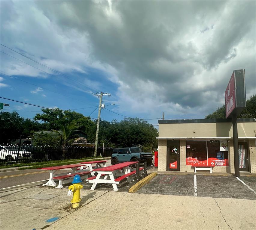 A commercial building exterior features red picnic tables, a yellow fire hydrant, and a sign — 6617 N NEBRASKA AVENUE, TAMPA, FL