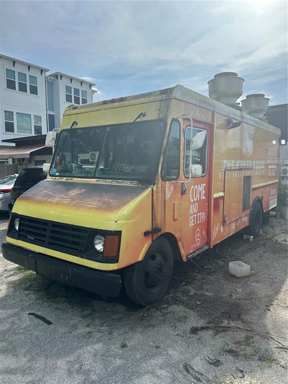A yellow and orange food truck is parked on a gravel lot near a building — 6617 N NEBRASKA AVENUE, TAMPA, FL