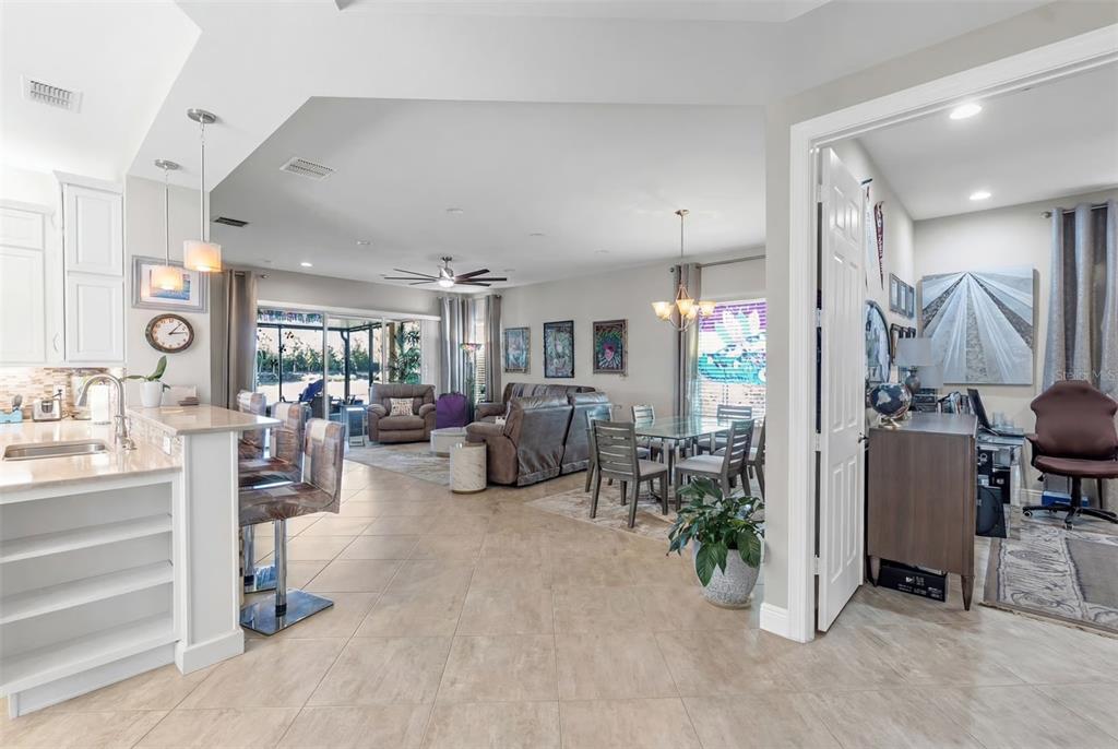 An open-concept living and dining area features tile flooring, a kitchen island, and a home office — 4912 SANDY GLEN WAY, WIMAUMA, FL