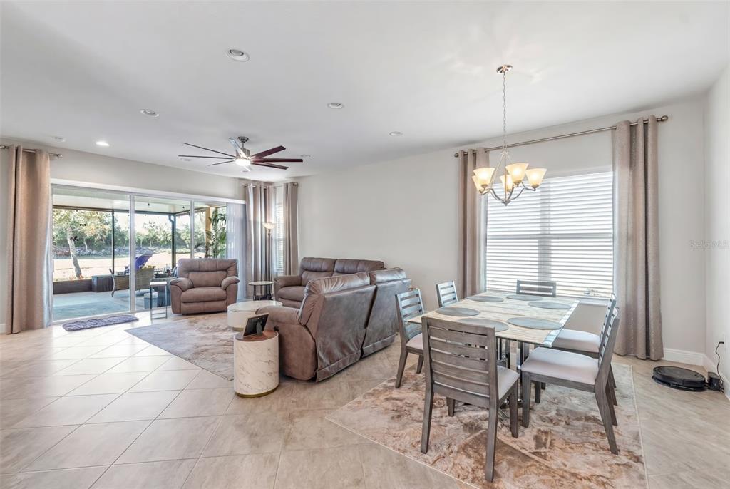 An open-concept living and dining area features tile flooring, a ceiling fan, and sliding doors — 4912 SANDY GLEN WAY, WIMAUMA, FL