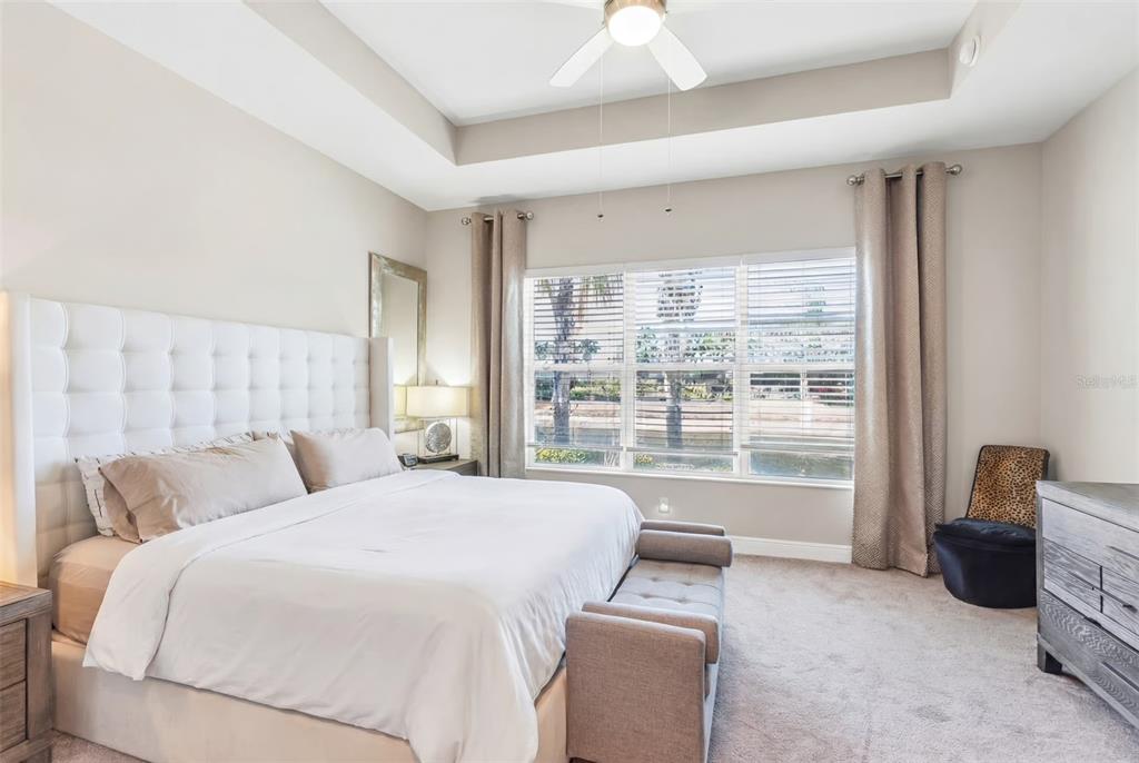 A bedroom features a tufted white headboard, a tray ceiling, and a window with curtains — 4912 SANDY GLEN WAY, WIMAUMA, FL