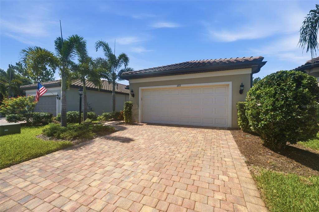 A paved driveway leads to the garage of a house with a tiled roof — 6713 ALSTEAD CIRCLE, BRADENTON, FL