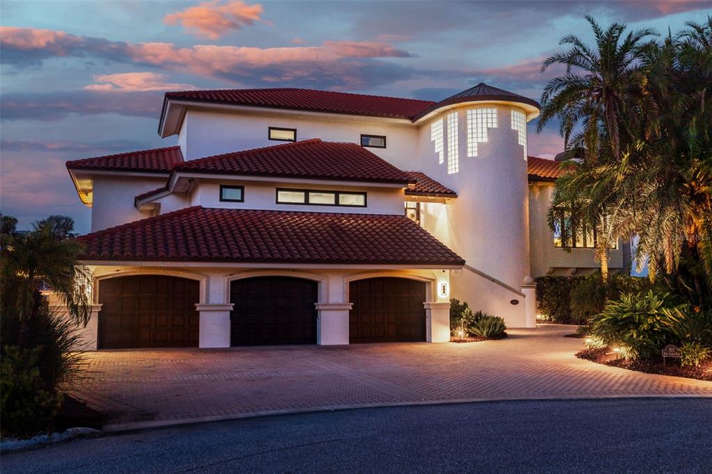 A multi-story house with a red tile roof, three garage doors, and a circular tower — 101 9TH STREET E, TIERRA VERDE, FL