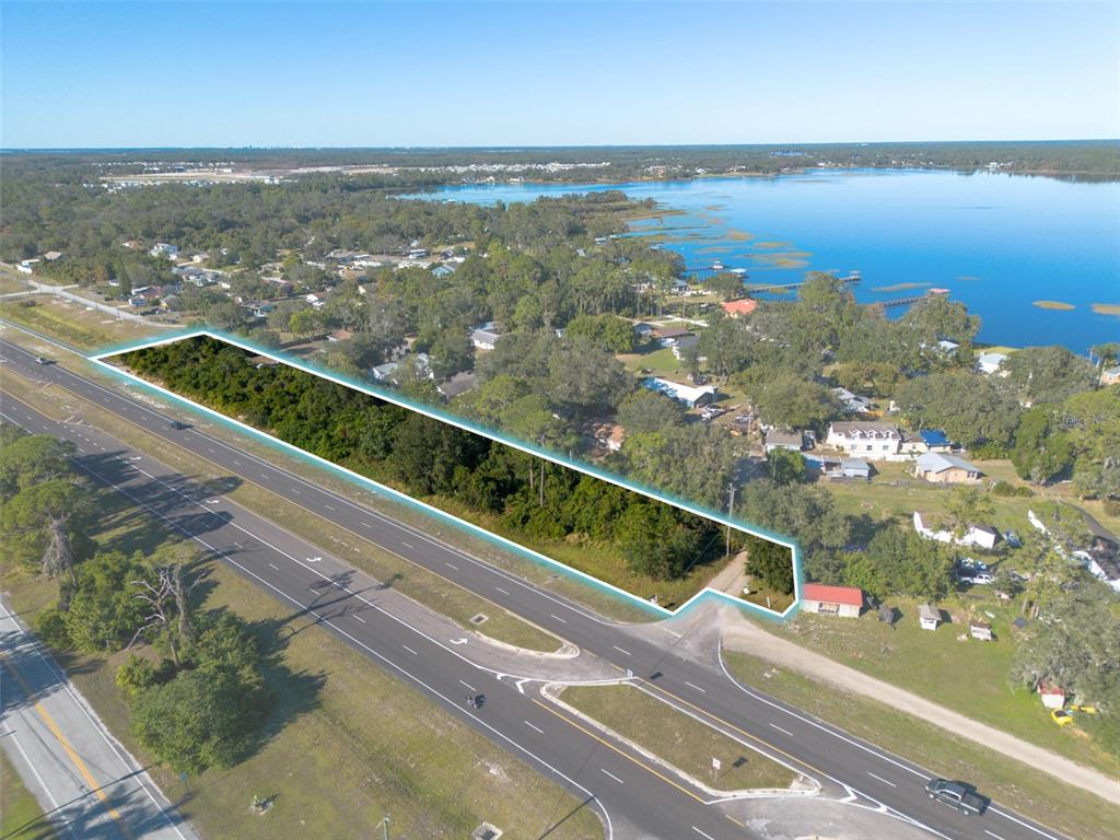 An aerial view shows a long, rectangular wooded lot adjacent to a multi-lane highway — E IRLO BRONSON MEMORIAL HIGHWAY UNIT 0220, ST CLOUD, FL