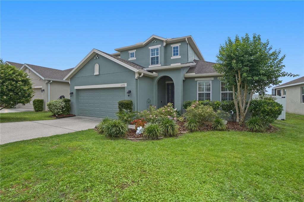 A two-story house with a green stucco exterior, a two-car garage, and a landscaped yard — 2296 NATOMA BOULEVARD, MOUNT DORA, FL