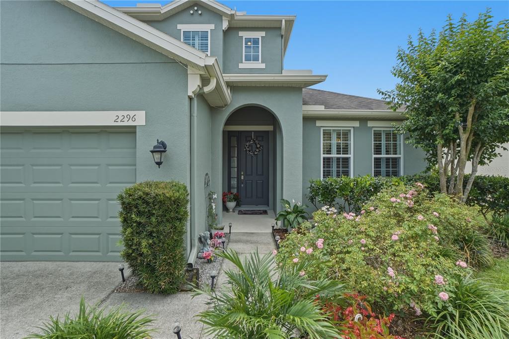The exterior of a two-story house features a garage, arched entryway, and landscaped front yard — 2296 NATOMA BOULEVARD, MOUNT DORA, FL