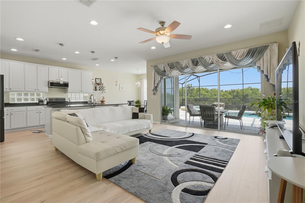 A living room with a white sectional, patterned rug, and sliding doors opening to a pool — 2296 NATOMA BOULEVARD, MOUNT DORA, FL