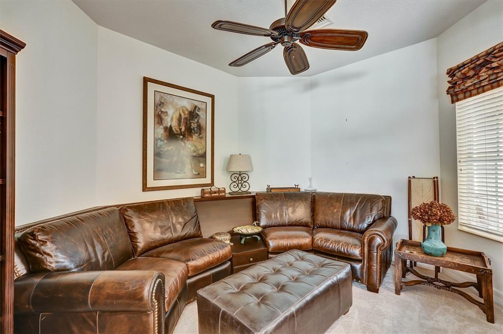 A room features a brown leather sectional sofa, a matching ottoman, and a ceiling fan — 7910 RIVER PRESERVE DRIVE, BRADENTON, FL