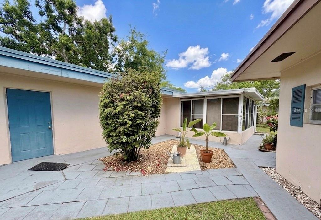 A paved courtyard sits between two sections of a house with a central garden bed — 3112 SE 29TH TERRACE, OKEECHOBEE, FL