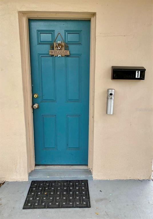A teal front door with a welcome sign, a black mailbox, and a floor mat — 3112 SE 29TH TERRACE, OKEECHOBEE, FL