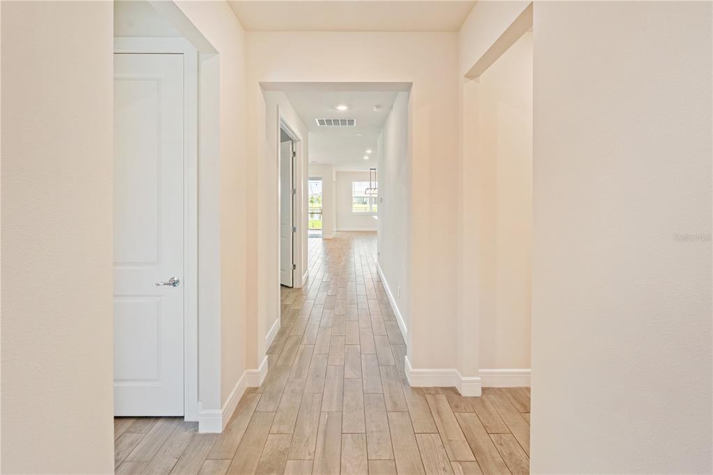 A hallway with light wood-look tile flooring leads toward an open living area — 1994 SPRING SHOWER CIRCLE, KISSIMMEE, FL