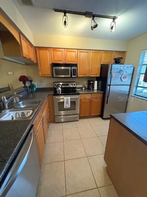 A kitchen features light wood cabinets, stainless steel appliances, and tile flooring — 10160 SAILWINDS BOULEVARD S UNIT 206, LARGO, FL