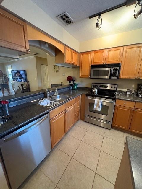 A kitchen features stainless steel appliances, wood cabinets, and tile flooring — 10160 SAILWINDS BOULEVARD S UNIT 206, LARGO, FL