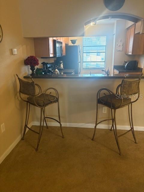 A kitchen breakfast bar with two metal stools sits in front of a window — 10160 SAILWINDS BOULEVARD S UNIT 206, LARGO, FL