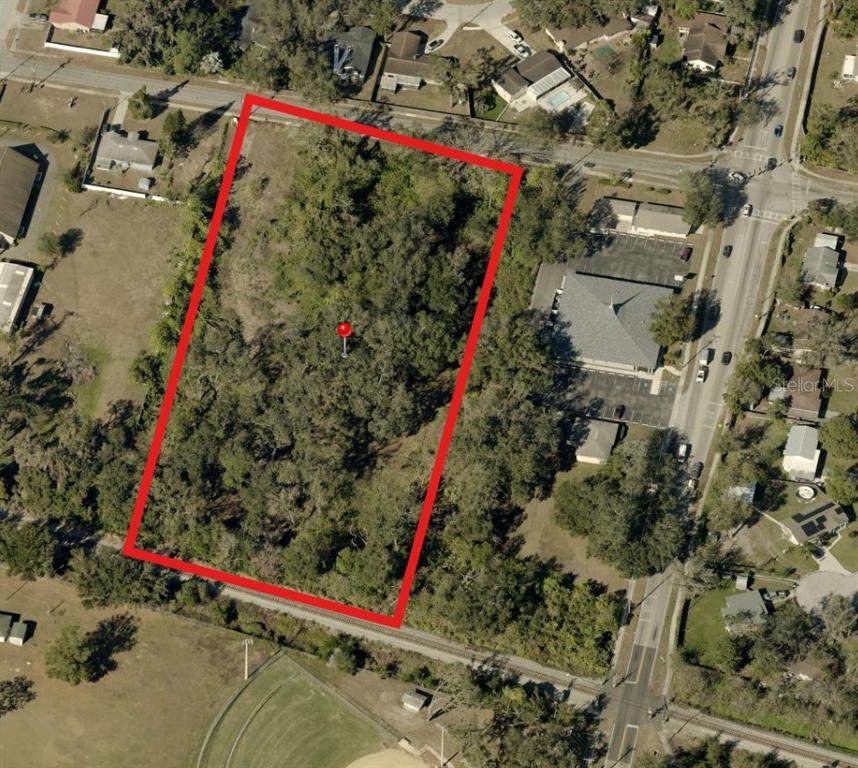 An aerial view shows a rectangular, tree-covered vacant lot outlined in red — 521 E CLAY AVENUE, BRANDON, FL