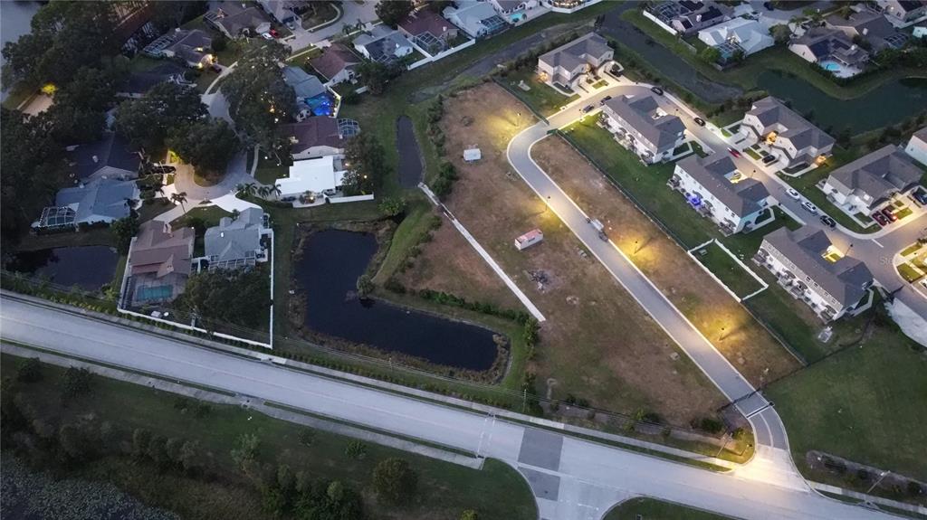 An aerial view shows a residential neighborhood with a vacant lot and a small pond — WHITNEY ROAD, CLEARWATER, FL
