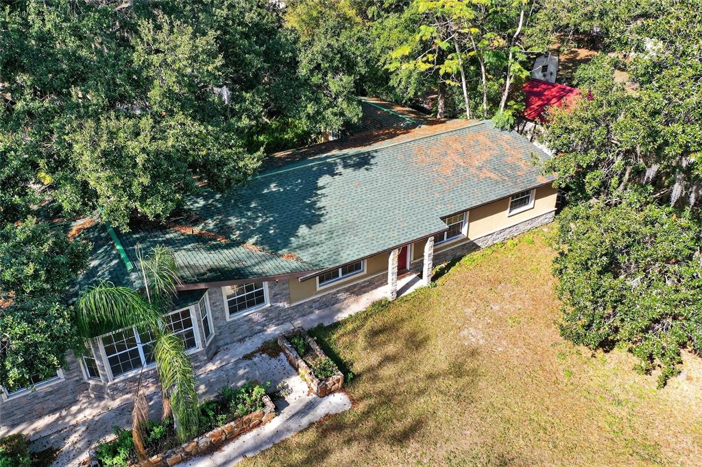 An aerial view of a single-story house with a green roof and stone facade — 17220 ESTES ROAD, LUTZ, FL