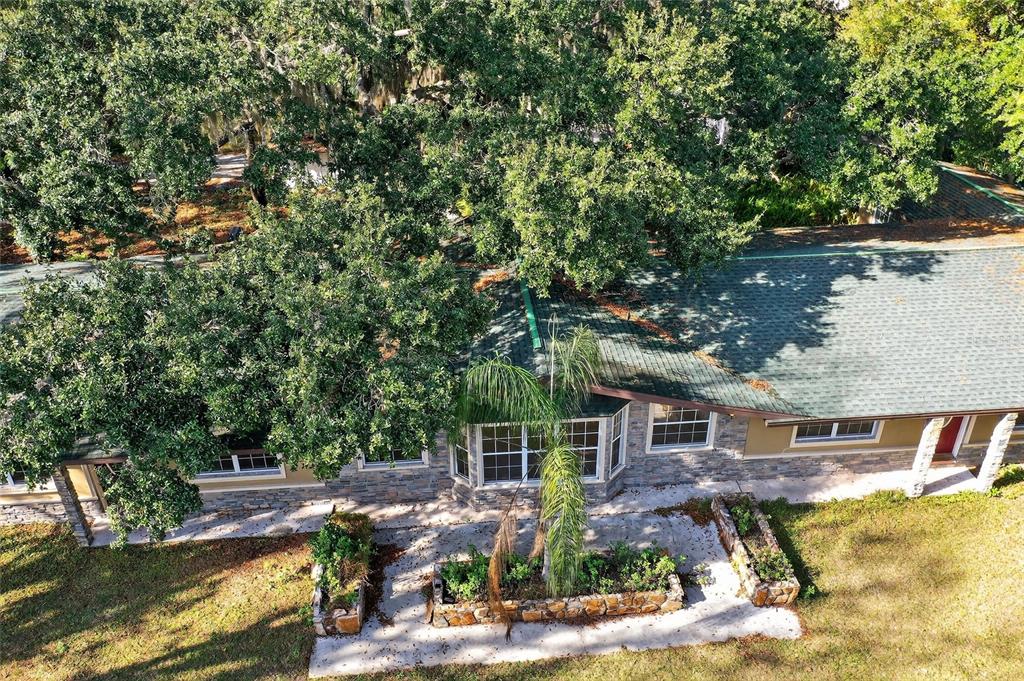 An aerial view of a house with a green roof, stone siding, and a patio — 17220 ESTES ROAD, LUTZ, FL