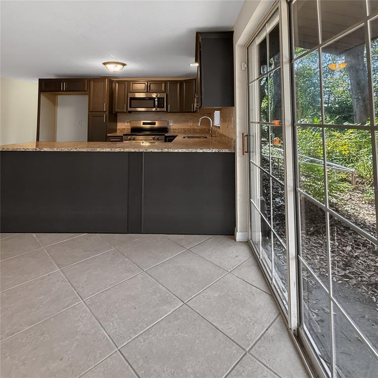 A kitchen with dark cabinets, granite countertops, and a sliding glass door to the outside — 17220 ESTES ROAD, LUTZ, FL