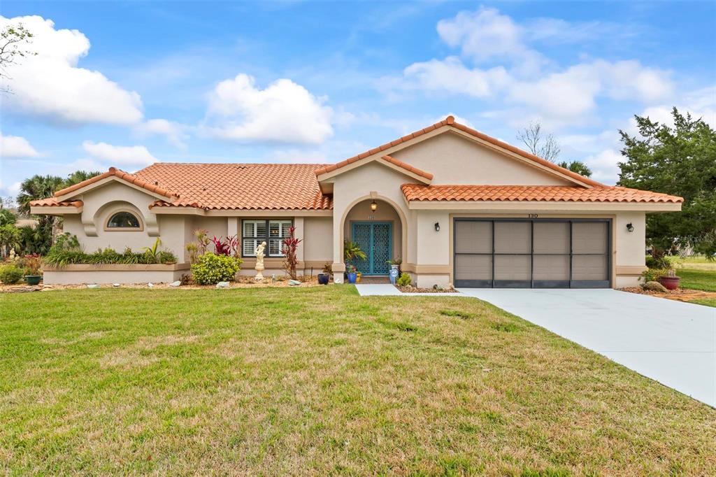A single-story house with a terracotta tile roof, beige stucco exterior, and a two-car garage — 130 BAYSIDE DRIVE, PALM COAST, FL