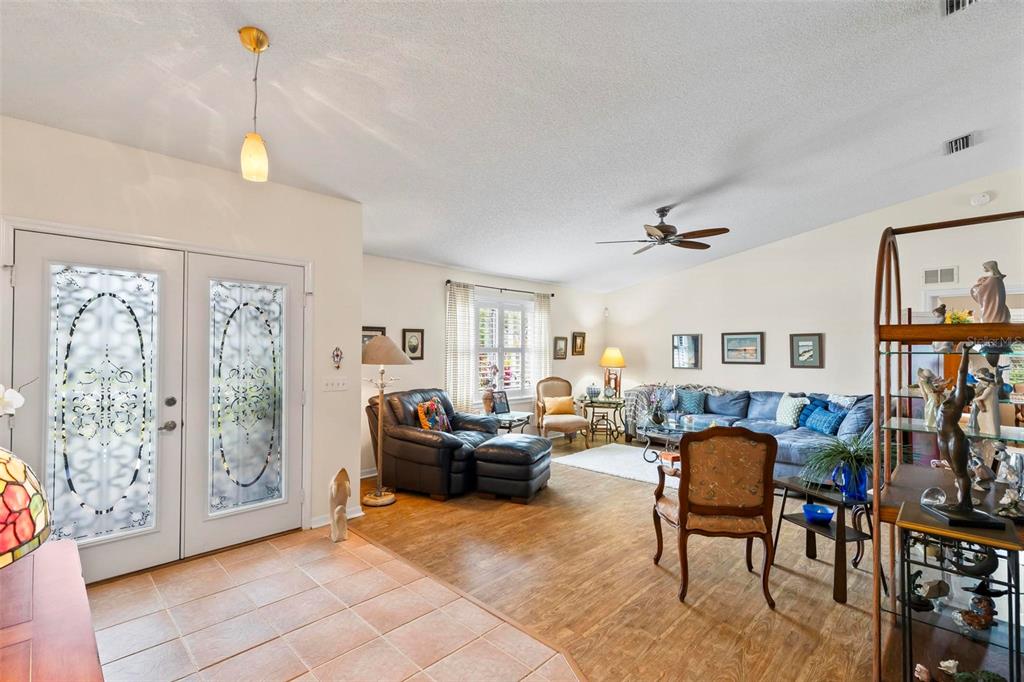 A living room with tile flooring at the entrance, wood-look floors, and a blue sectional sofa — 130 BAYSIDE DRIVE, PALM COAST, FL