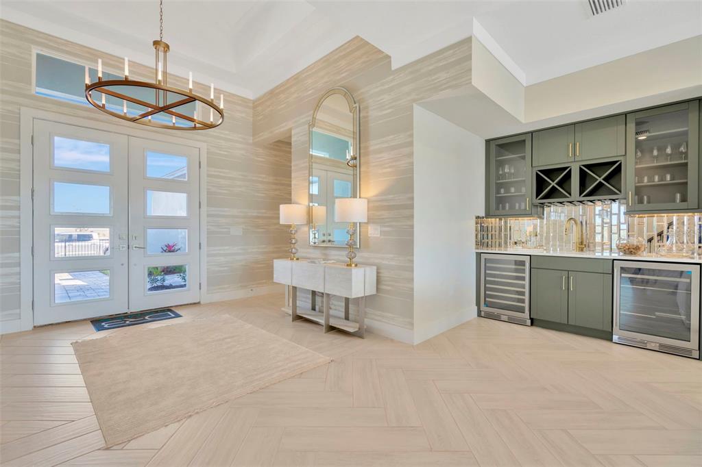 An entryway features a herringbone floor, a wet bar with green cabinets, and a chandelier — 8530 SALMAR LOOP, PARRISH, FL