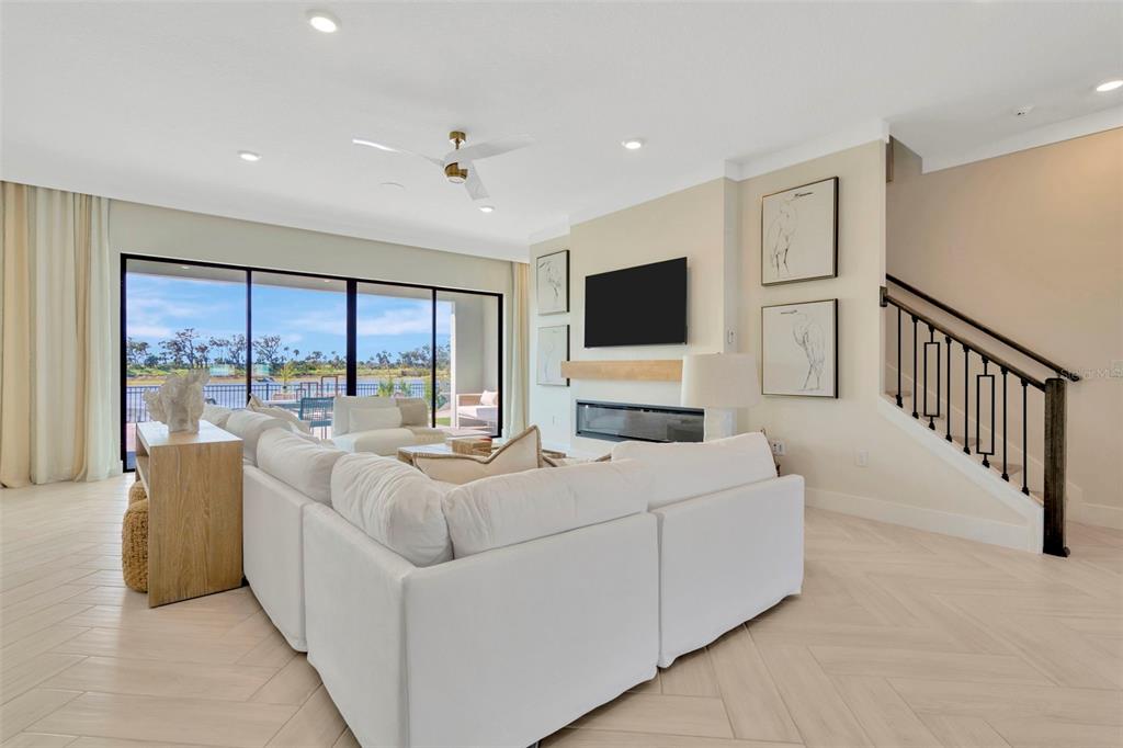 A bright living room features a white sectional sofa, fireplace, and sliding doors overlooking water — 8530 SALMAR LOOP, PARRISH, FL