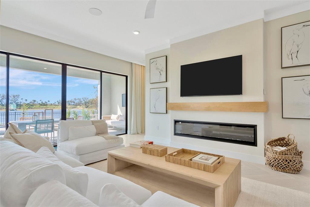 A living room features a fireplace, wall-mounted television, white furniture, and sliding glass doors — 8530 SALMAR LOOP, PARRISH, FL