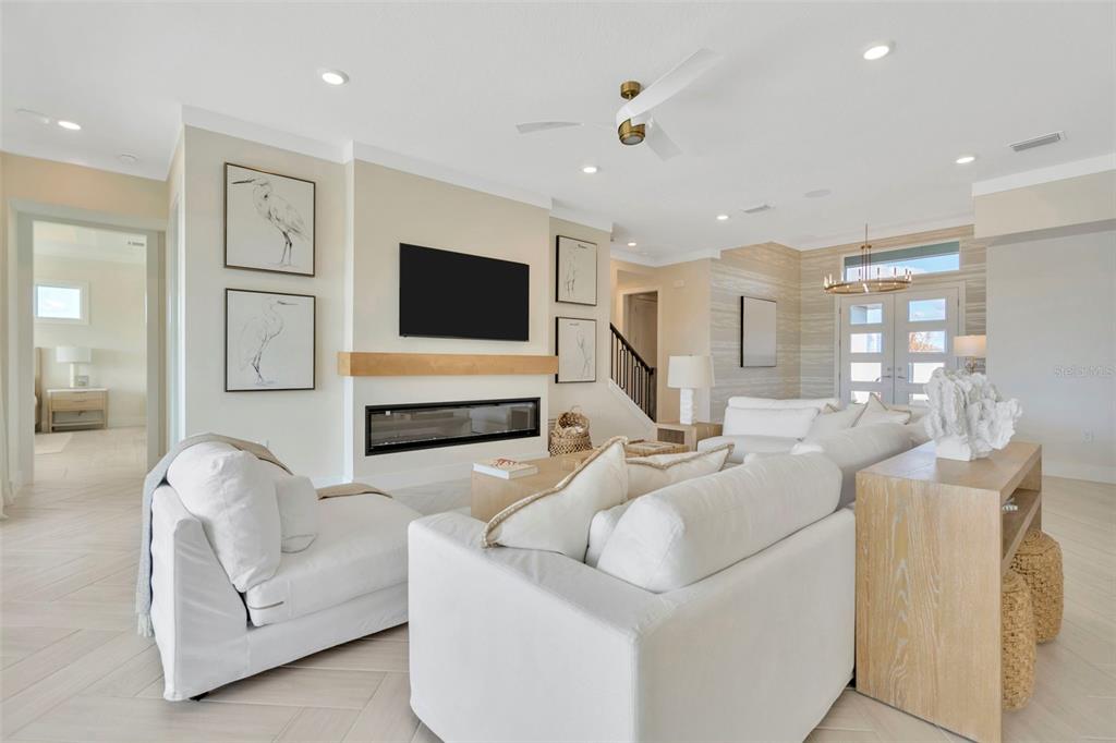A bright living room features a fireplace, wall-mounted television, white furniture, and light wood flooring — 8530 SALMAR LOOP, PARRISH, FL